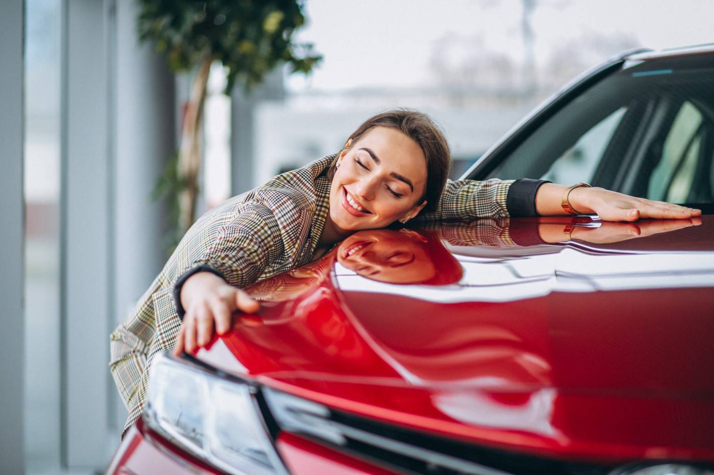 Happy woman hugging red car after buying used car with the ultimate used car buying guide