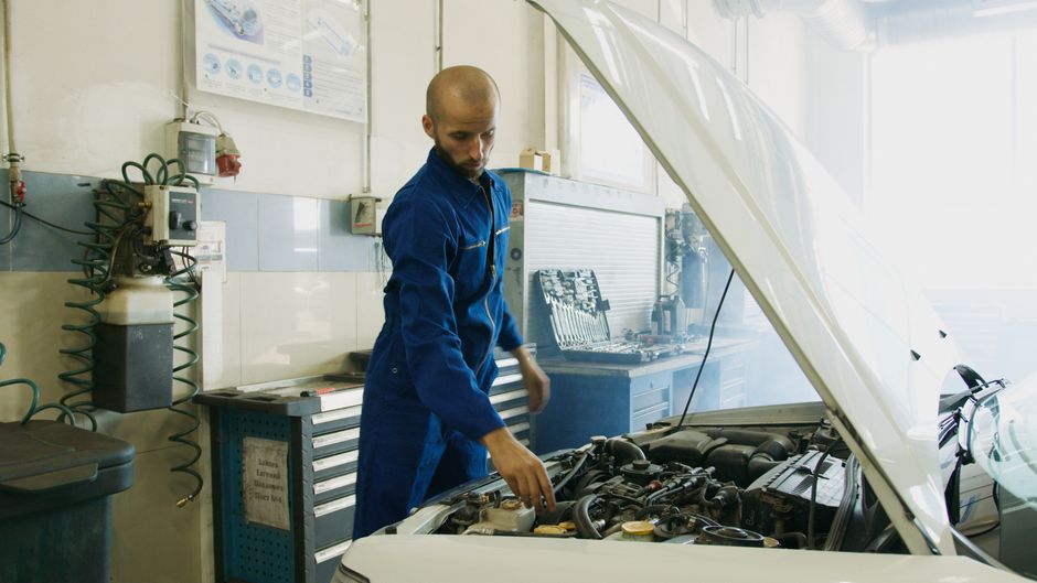 Mechanic inspecting under the hood of a used car for sale under $10,000 in  Cumming GA