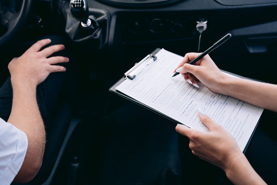 Close-up of a customer signing title paperwork after accepting a cash offer for their used car