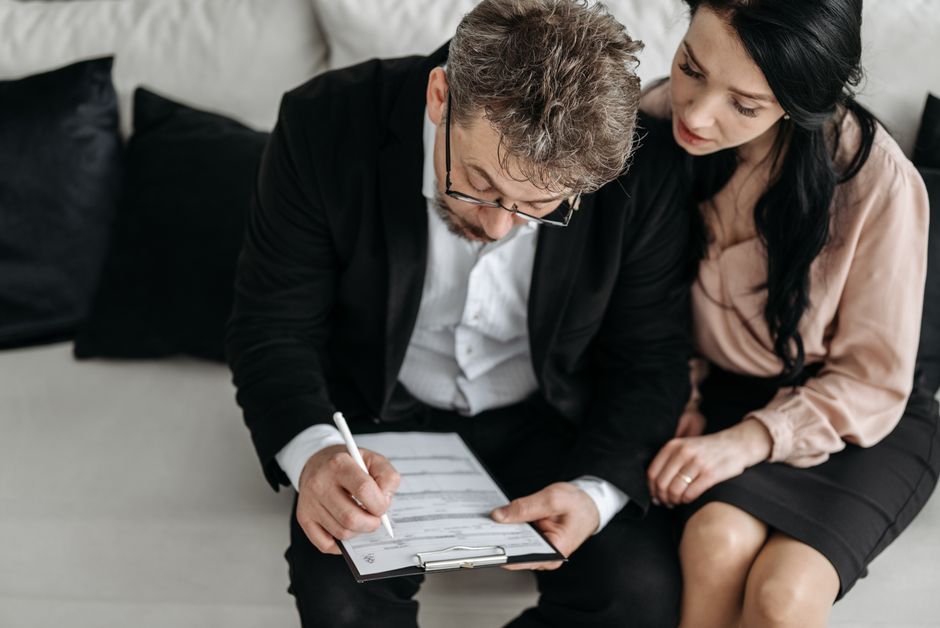Couple reviewing paperwork during a guided used car buying process with a dealership advisor